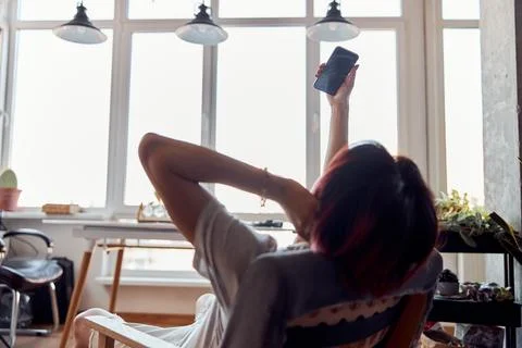 Guy sitting opposite the window while using smartphone Stock Photos