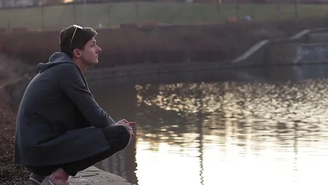 The  guy is sitting on the shore of the pond. He thinks about the eternal Stock Footage 74074279