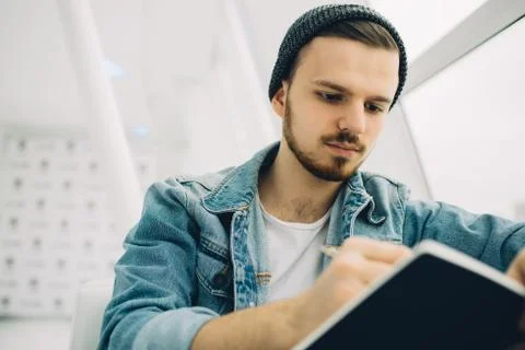Guy is sitting on sofa and writing notes Stock Photos