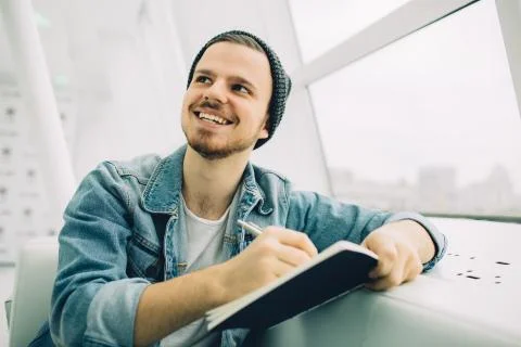 Guy is sitting on sofa and writing notes Foto stock