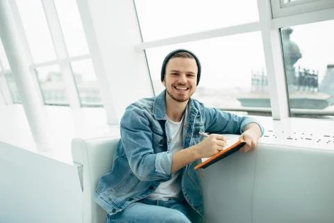 Guy is sitting on sofa and writing notes Stock Photos