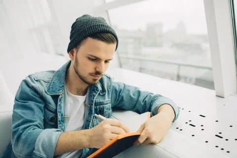 Guy is sitting on sofa and writing notes Stock Photos
