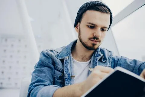 Guy is sitting on sofa and writing notes Stock Photos