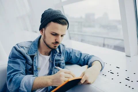 Guy is sitting on sofa and writing notes Stock Photos
