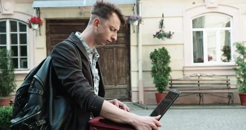 Guy sitting on the street and working on a laptop. attractive man with Stock Footage 161755449