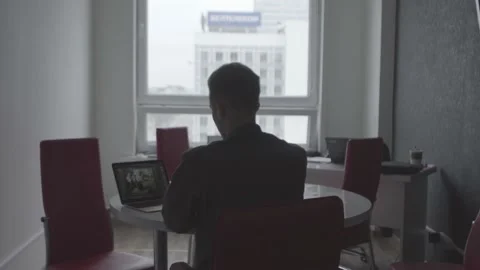 The guy is sitting at the table by the laptop. The guy writes, draws. Stock Footage 130218981