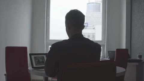 The guy is sitting at the table by the laptop. The guy writes, draws. Stock Footage 130219052