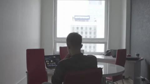 The guy is sitting at the table by the laptop. The guy writes, draws. Stock Footage 130228931