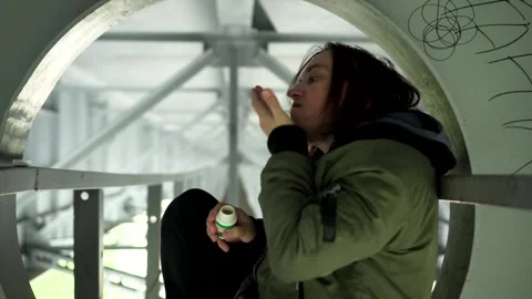 The guy is sitting under the bridge and taking pills. Dependent people 스톡 동영상 131552655