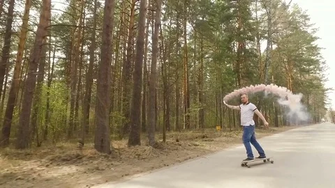 Guy skate on logboard in a forest with a color smoke grenade , slow motion Stock Footage 75337794