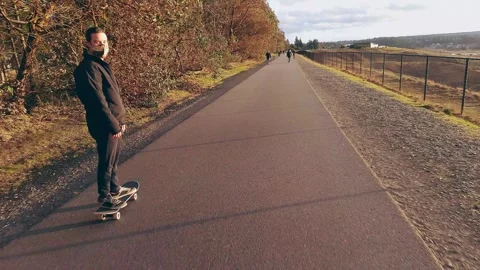 Guy Skateboarding on trail with mask on Stock Footage 285665645