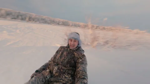 A guy slides down a high slide in the snow on a round inflatable sleigh. Stock Footage 325860390