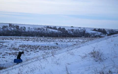The guy slides down the hill, slide, sleigh, winter, frost. Stock Photos