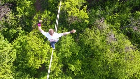 The guy on the sling is engaged in slackline at high altitude. View from above Stock Footage 131851943
