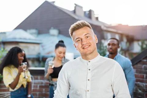 Guy smiling on camera with three friends on background 스톡 사진