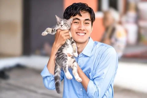 A guy smiling while hugging his cat. Handsome men and a cute kitten Stock Photos