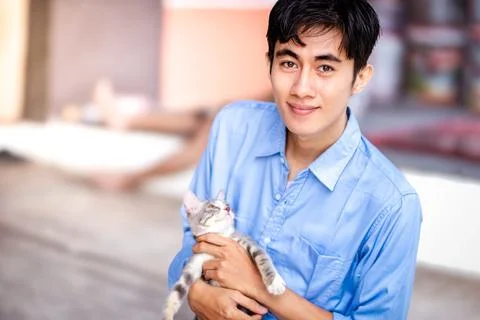 A guy smiling while hugging his cat. Handsome men and a cute kitten Stock Photos