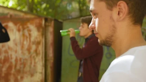 Guy smokе and take a sip of beer. On the background teenagers drinking beer Stock Footage 118701340