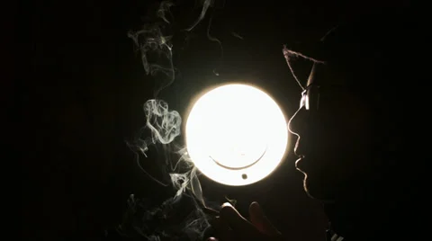 A guy smoke cigarette in front of the light Stock Footage 39818542