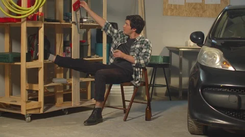 The guy smokes and fools around with tools in the garage 스톡 동영상 128181003