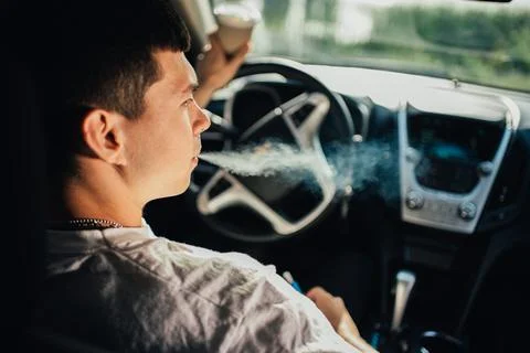 A guy smokes in a car while driving car Stock Photos