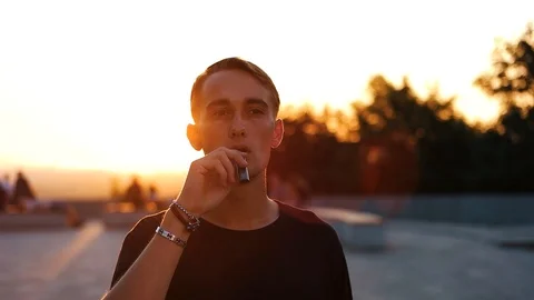 Guy smokes an electronic cigarette at sunset Stock Footage 118578391