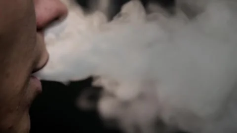 The guy smokes a vape. Close up on a black background. Nicotine addiction concep Stock Footage 292257759