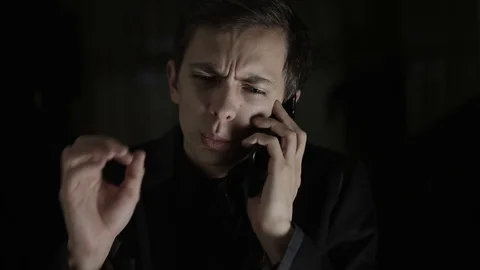 The guy speaks on the phone cheerfully, smiling and explaining something Stock Footage 120597479