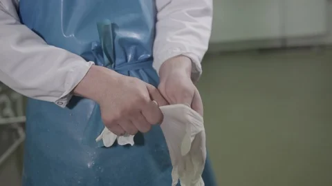 Guy in special clothes puts on white gloves in a sausage factory Stock Footage 122442106