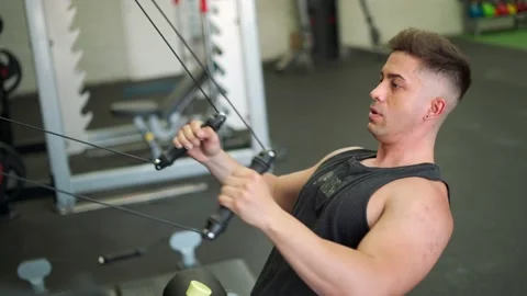 Guy in sportswear pulling rope on exercise machine during workout in contempo Stock Footage 197571952