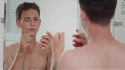 Guy Spraying Armpits with Deodorant or Perfume in front of Mirror Vidéo 270136549