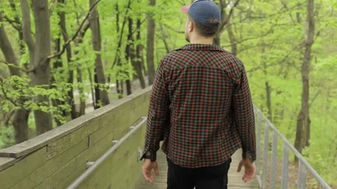 The guy in the spring forest walks on the bridge. Vídeos de archivo 188309563