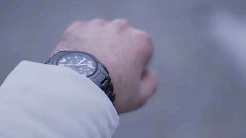 A guy is standing and looking at his watch. A guy in a white jacket 動画素材 130743183