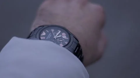 A guy is standing and looking at his watch. A guy in a white jacket Stock Footage 130743213