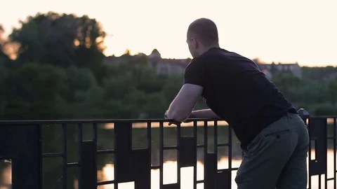 A guy is standing on a bridge and thinking about something Stock Footage