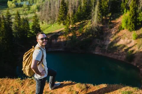 Guy standing on the cliff above the lake with the sky reflecting in it Stock Photos