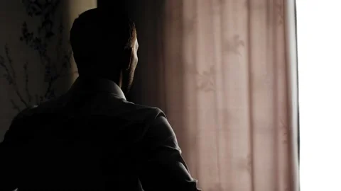 The guy is standing in a dark room and getting dressed. Side view Stock Footage 138272993