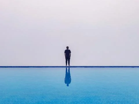 A guy standing at the edge of infinity pool with white foggy background Stock Photos