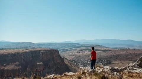 A guy standing on the edge of a mountain overlooking the landscape Stock Photos