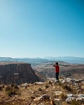 A guy standing on the edge of a mountain overlooking the landscape 库存照片