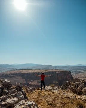 A guy standing on the edge of a mountain overlooking the landscape Stock Photos