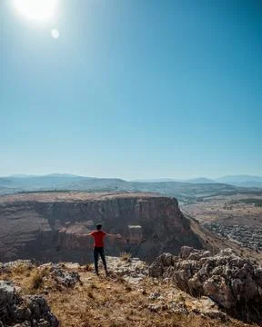 A guy standing on the edge of a mountain overlooking the landscape Stock Photos