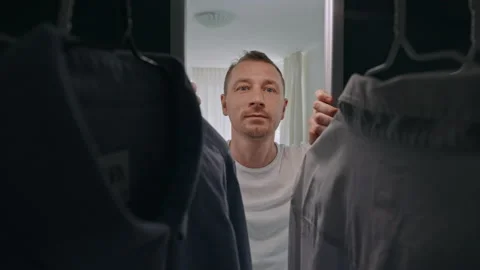 Guy standing in front of closet chooses shirt Video stock 232286367