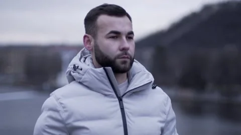 The guy is standing. The guy looks around. Guy in a white jacket Stock Footage 130743346