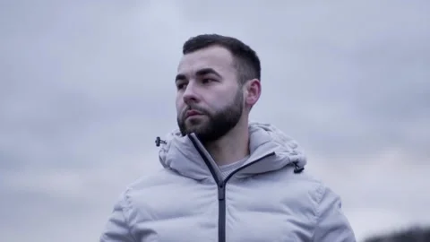 The guy is standing. The guy looks around. Guy in a white jacket Stock Footage 130743374