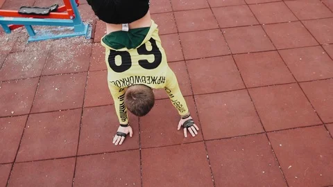The guy is standing on his hands on the Playground. Sports exercises Stock Footage 129354509