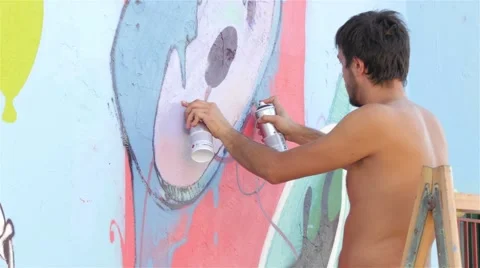 Guy standing on ladders and drawing graffiti on wall with spray, close up, 4k. 스톡 동영상 54760221