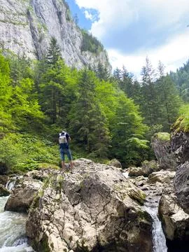 A guy is standing on large blocks of stone on a mountain river Stock Photos