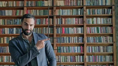 Guy Is Standing In The Library. He Points To The Side With His Finger. Vídeos de archivo 140222375