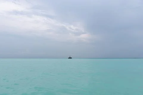 The guy is standing on a rock in the middle of the ocean and waving his arms. Stock Photos